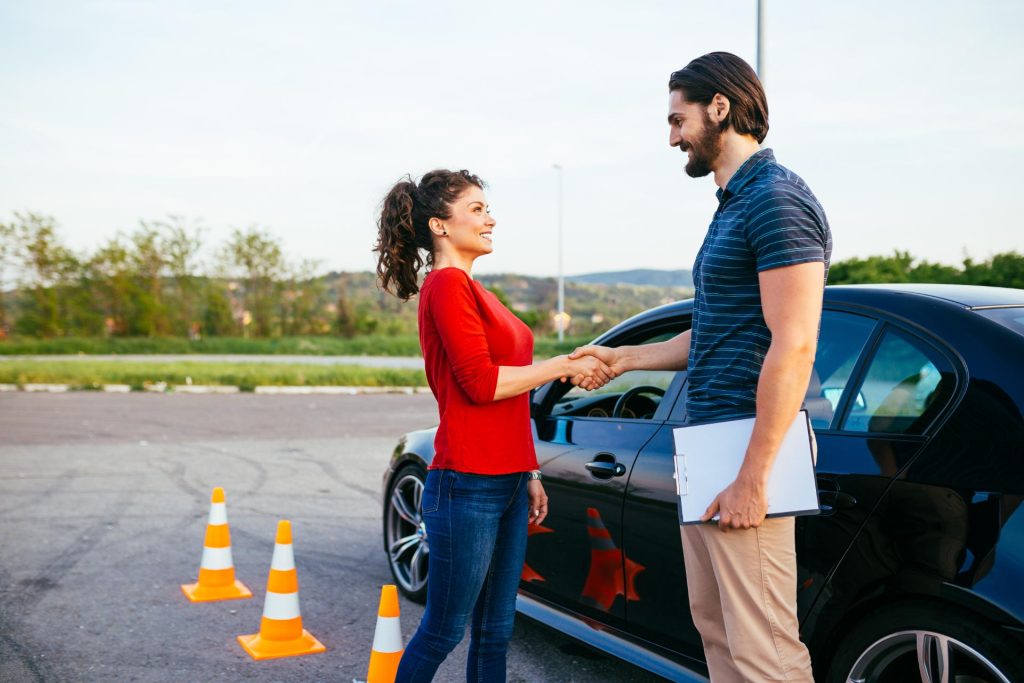 Instructor shaking the hands of a woman who subscribed for a driving lesson