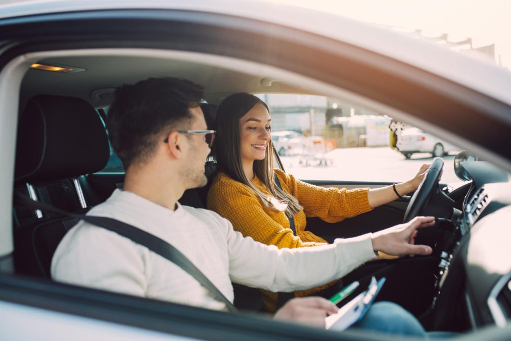 Woman learning how to drive with instructor next to her