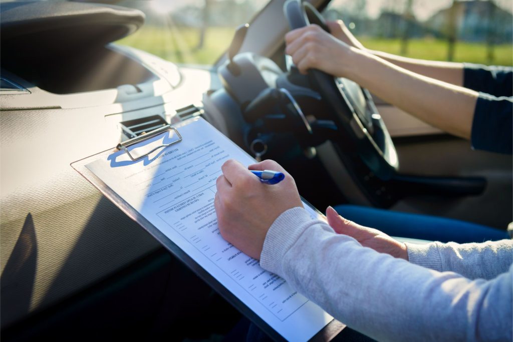 Person driving car with passenger taking notes